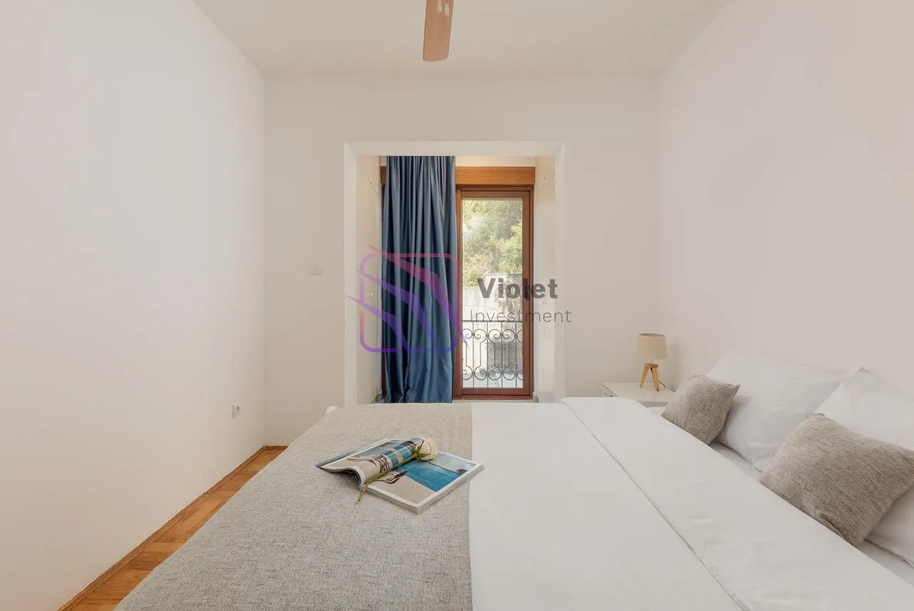 Svijetla spavaća soba sa bračnim krevetom i izlazom na balkon.
