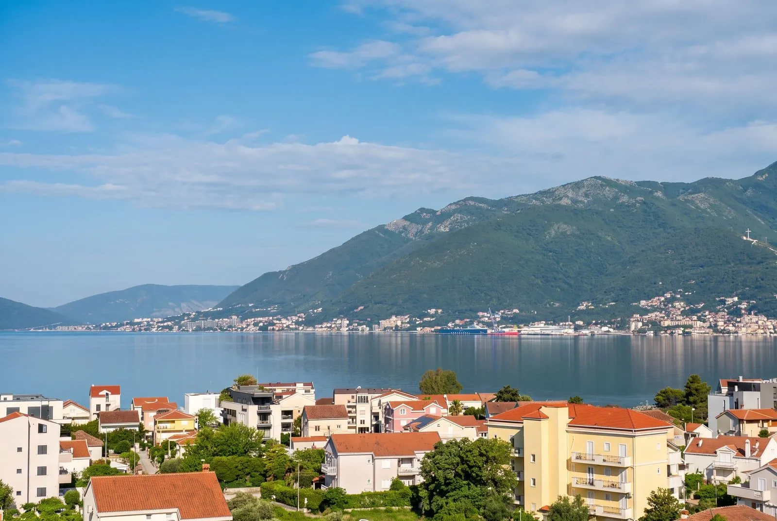 Pogled sa terase na zaliv, naselje i planine u pozadini.