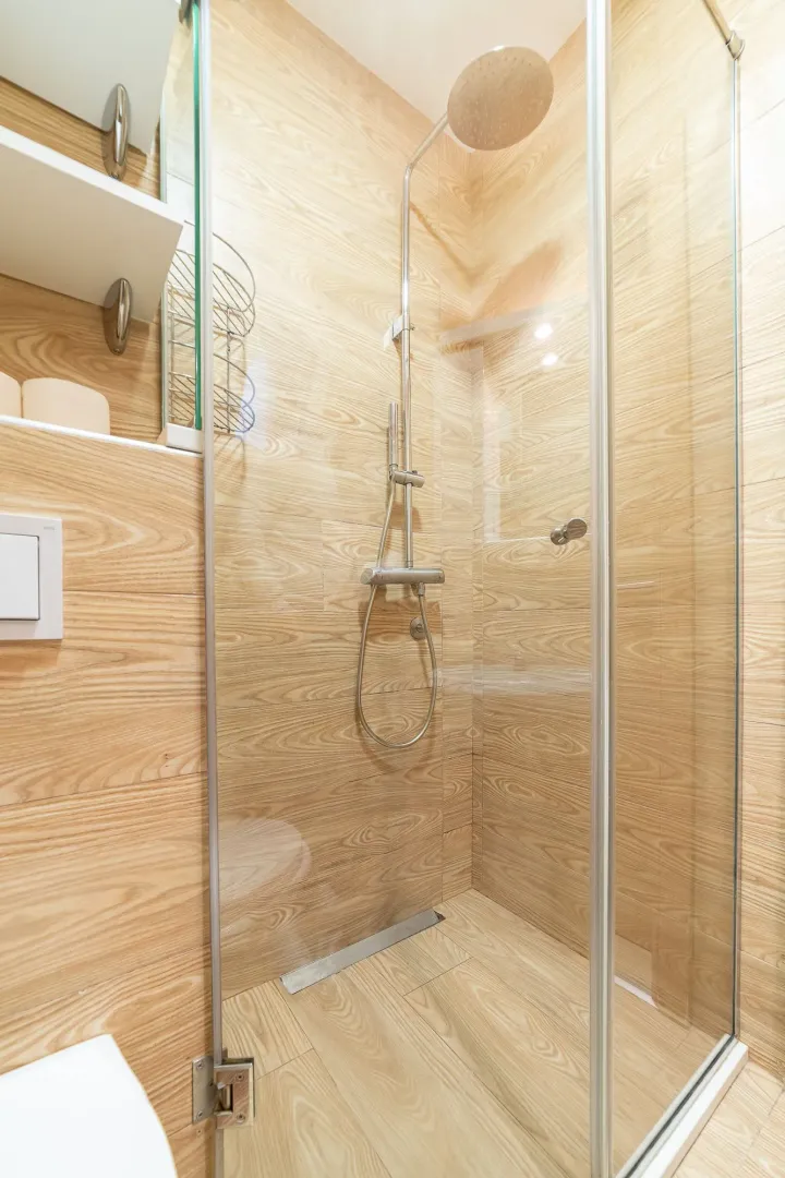 Modern shower cabin with wood-look tiles and chrome fixtures.