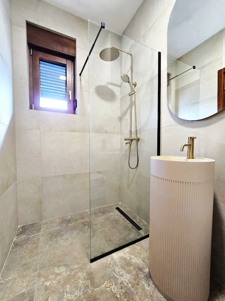 Modern bathroom with a shower cabin, washbasin, and window.