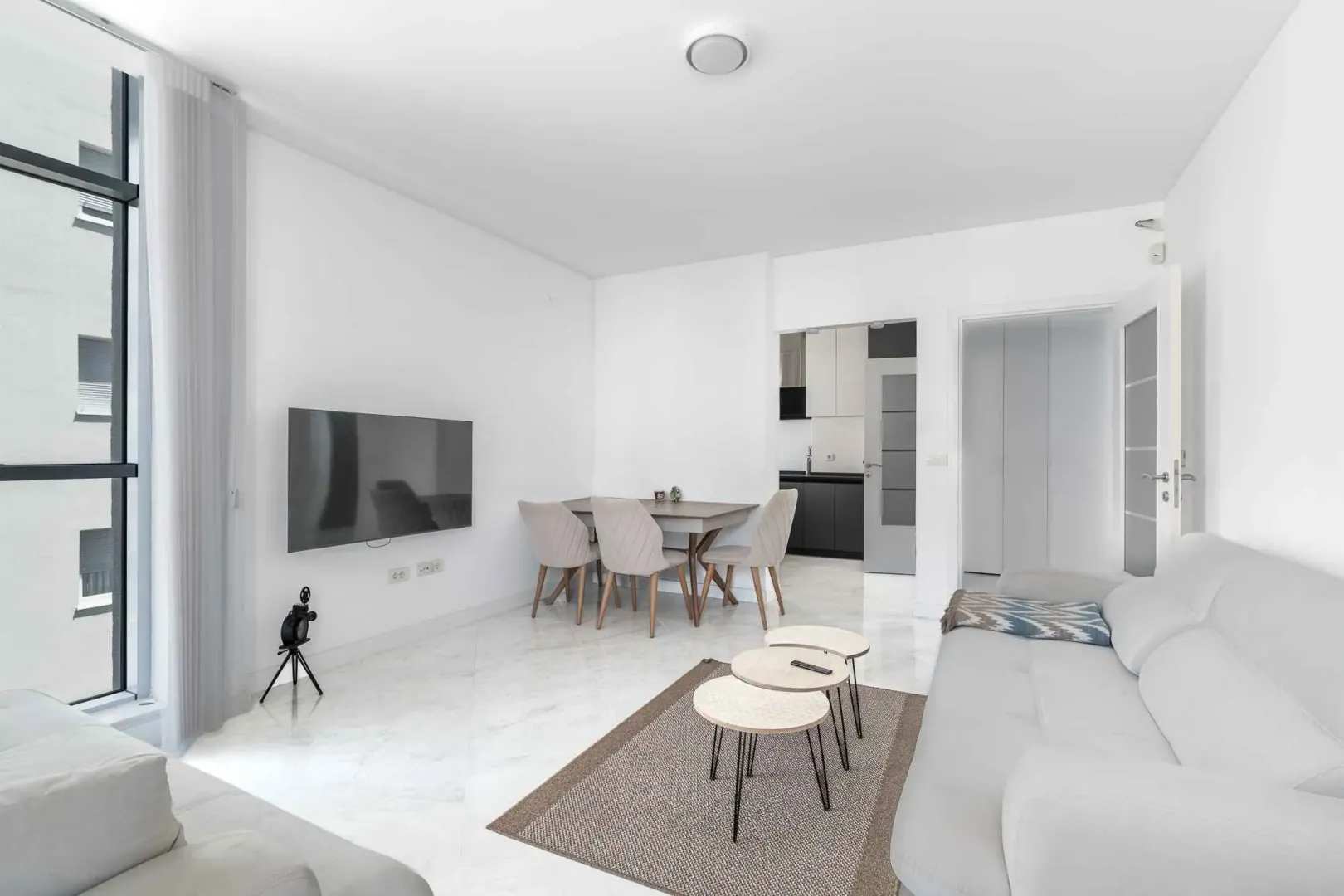 Bright living room with a sofa set, dining area, and access to the terrace.