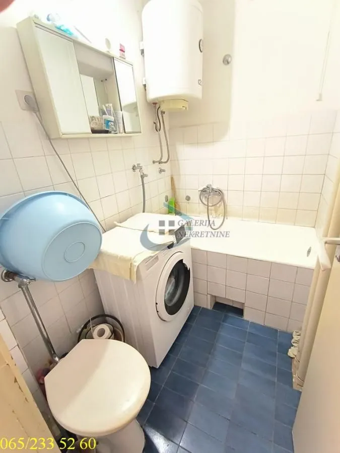 Manje kupatilo sa kadom, veš mašinom i WC šoljom.