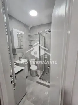 Small bathroom with a shower cabin, sink, toilet, and washing machine. - image 10