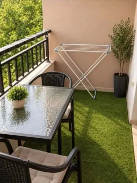 Furnished balcony with a table, chairs, and artificial grass on the floor. - image 12