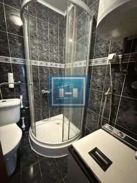 Manje kupatilo sa tuš kabinom, WC šoljom i tamnim pločicama. - image 8