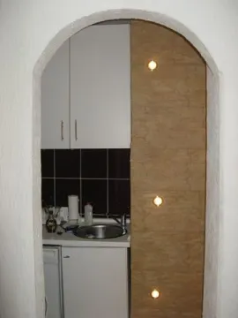 Small kitchen with white cabinets viewed through an arch. - image 7