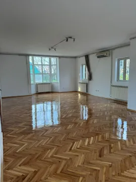 A spacious empty room with glossy parquet flooring and natural light. - image 11