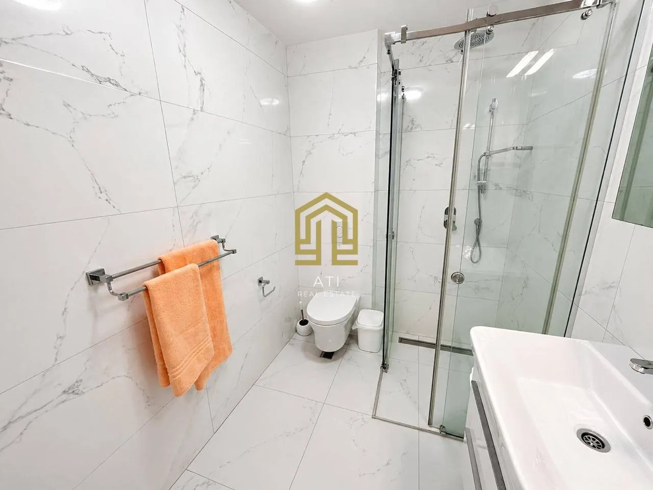 Modernly equipped bathroom with a walk-in shower lined with marble tiles.