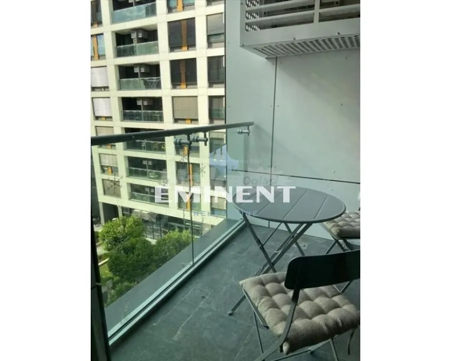 Manji namešteni balkon sa staklenom ogradom i pogledom na susedne zgrade.