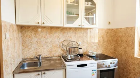 Small kitchen with a sink, stove, and white cabinets. - image 8