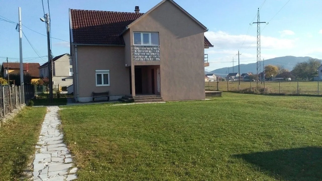 Dvospratna kuća sa prostranim dvorištem i zelenim travnjakom.