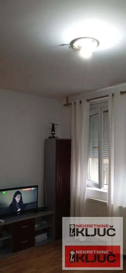 Manja dnevna soba sa televizorom i prozorom.
