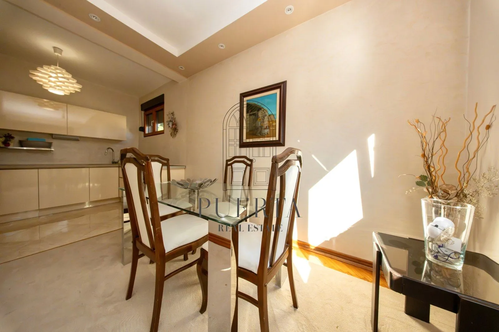 Dining area with a glass table and chairs, connected to the kitchen.