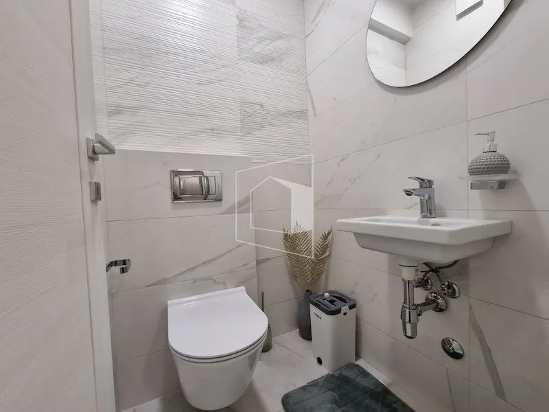 Moderno opremljeno kupatilo sa bijelim pločicama i ugradnim sanitarijama.