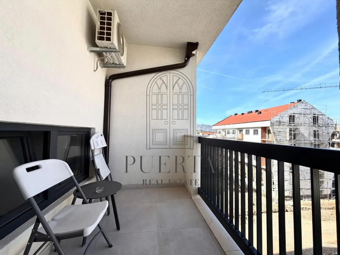 Small furnished balcony with a table and chairs.