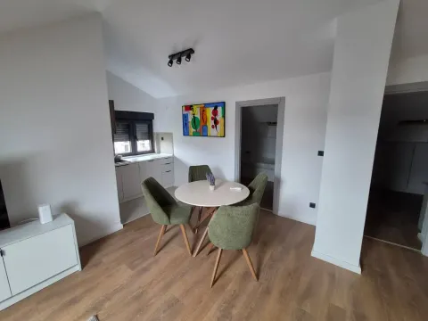 Dining area with a round table and green chairs connected to the kitchen. - image 3