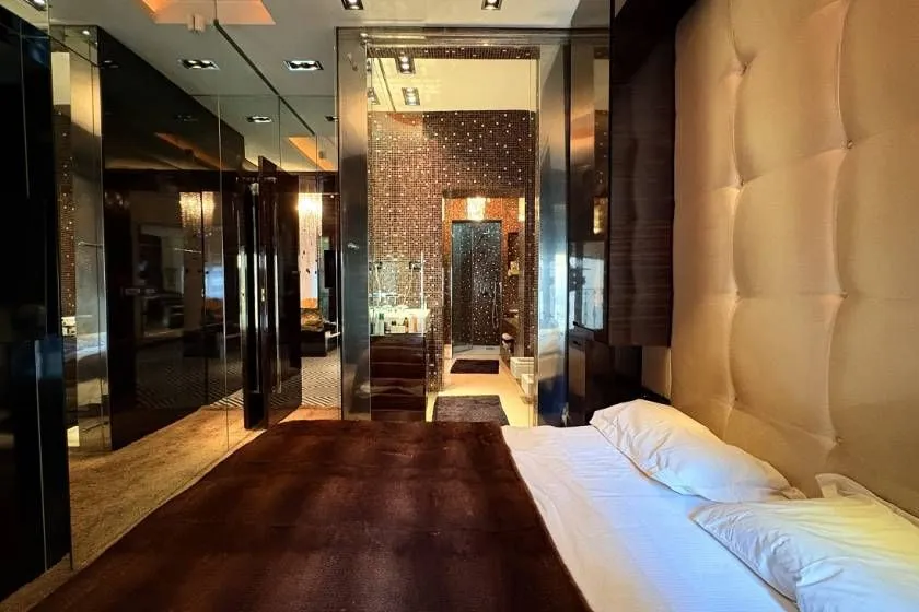 Luxuriously furnished bedroom with a large double bed and a view of the bathroom.