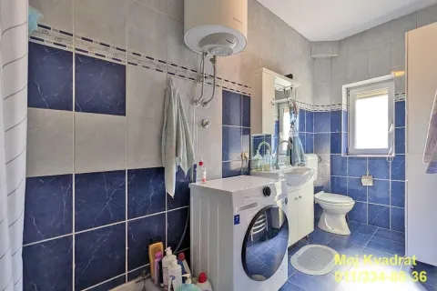 Kupatilo obloženo pločicama sa umivaonikom, toaletom i mašinom za veš. - image 9