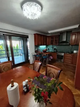 Trpezarija povezana sa kuhinjom sa drvenim nameštajem i izlazom na terasu. - image 38