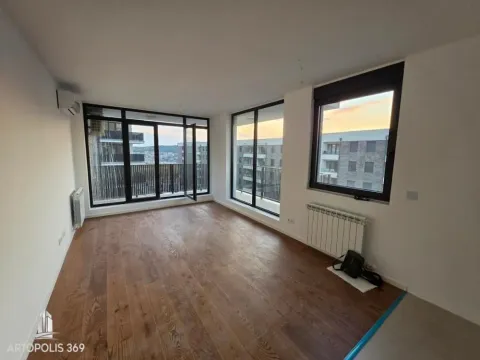 Empty living room with wooden flooring and large windows overlooking surrounding buildings. - image 4