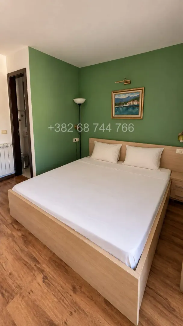 Spavaća soba sa bračnim krevetom i zelenim zidom.