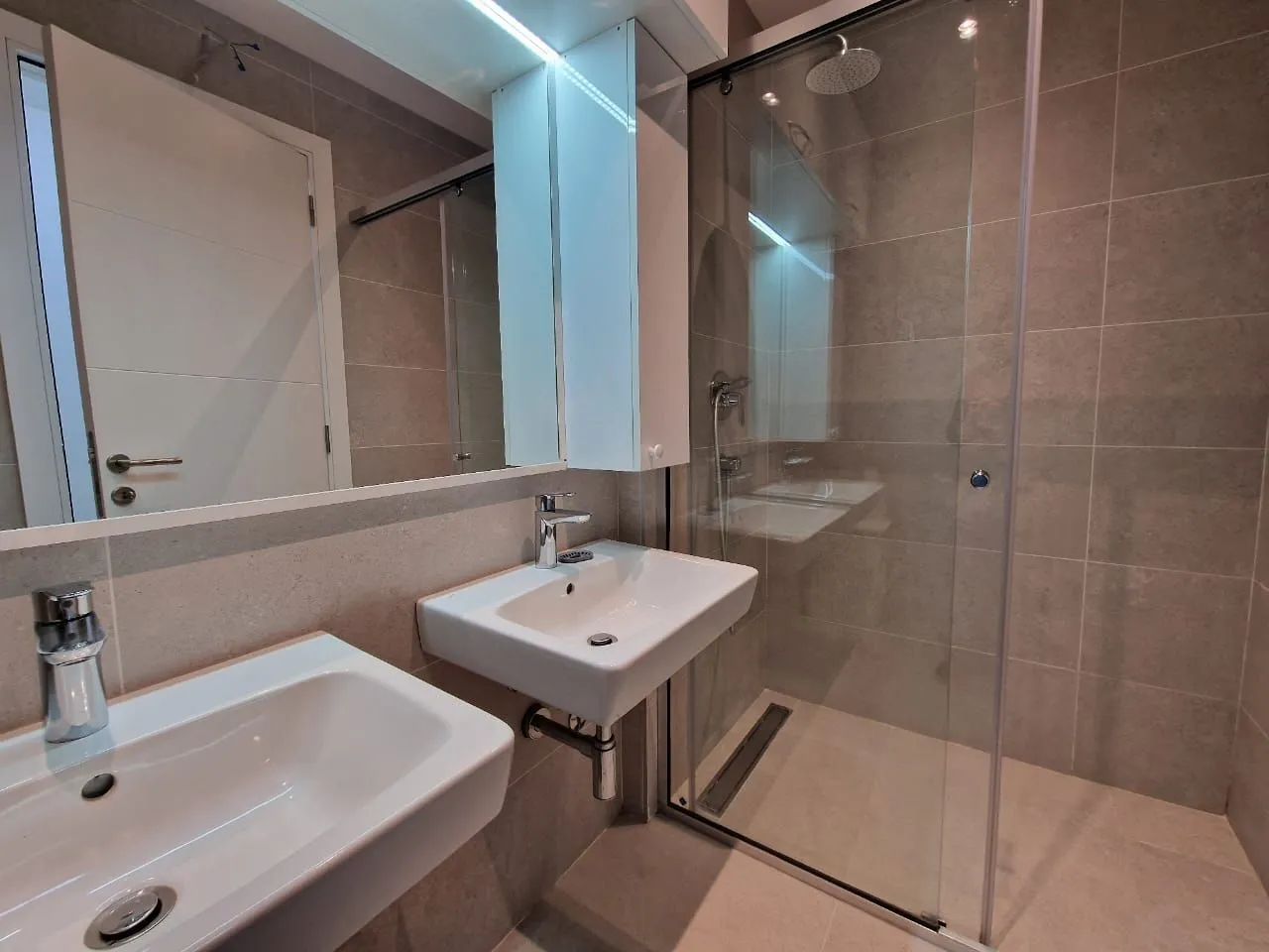 Modern bathroom equipped with two washbasins and a walk-in shower.