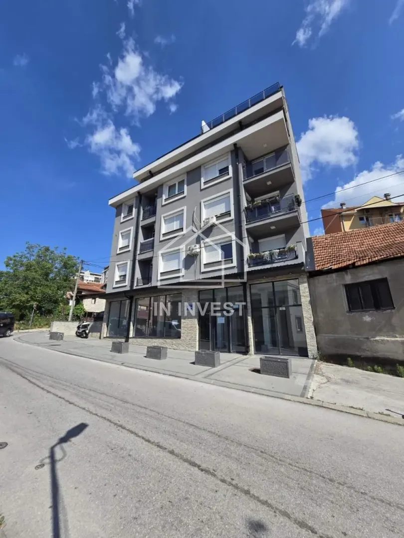 Exterior view of a modern residential building with commercial space on the ground floor.