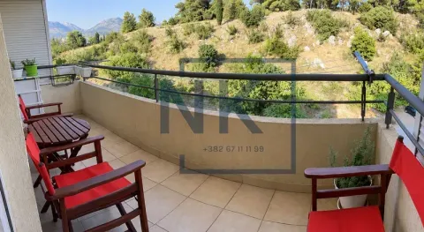 Namješten balkon sa drvenim stolom i crvenim stolicama i pogledom na prirodu. - image 8