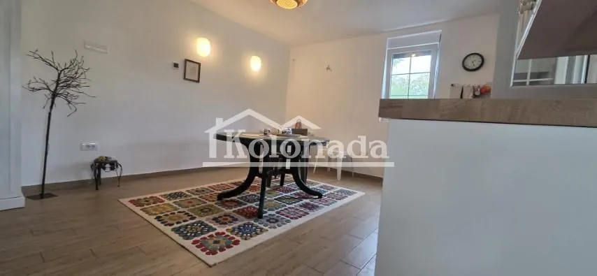 Trpezarija sa stolom i šarenim tepihom pored kuhinjskog pulta.