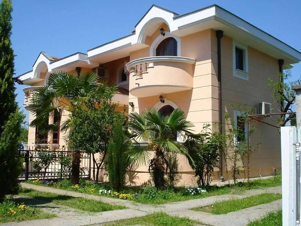 A two-story house with a landscaped yard and palm trees.