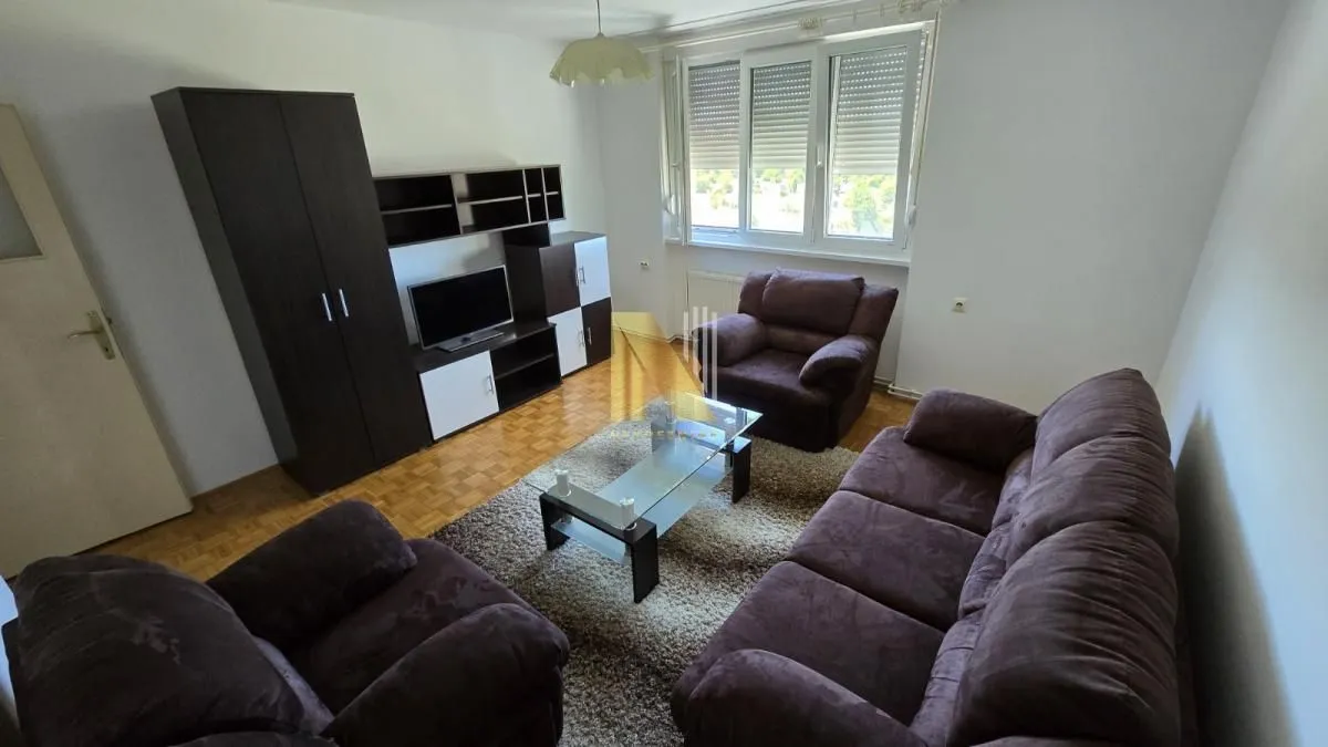 Nameštena dnevna soba sa garniturom za sedenje i televizorom.