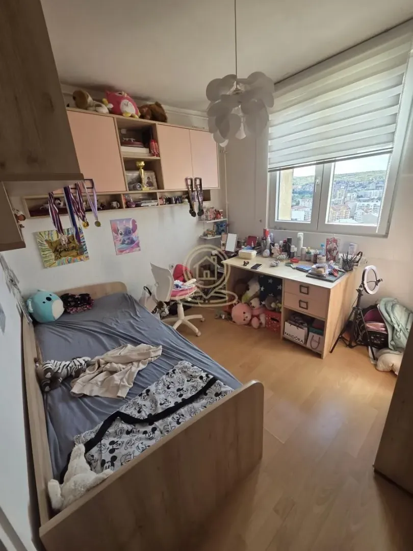 Children's bedroom with a bed, desk, and wall-mounted cabinets.