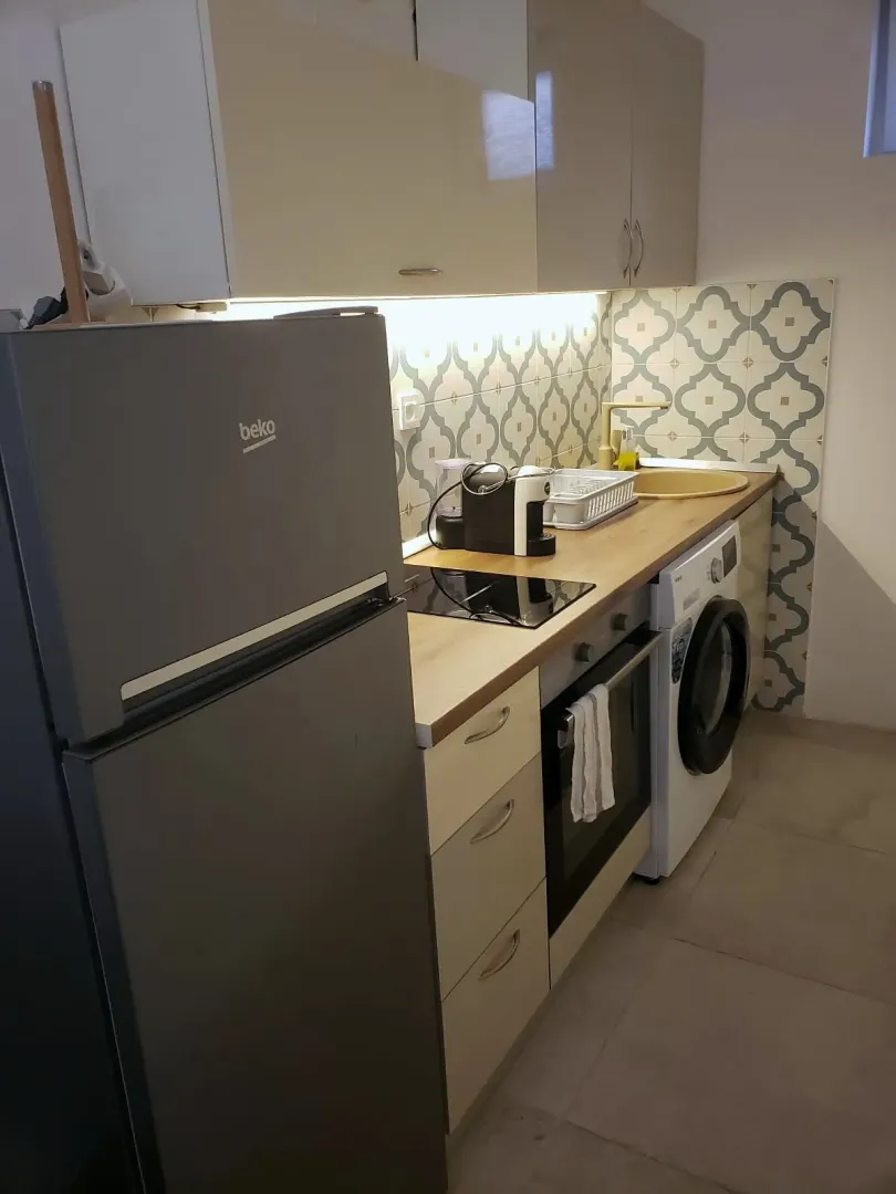 Manja kuhinja sa frižiderom, šporetom i ugrađenom mašinom za pranje veša.
