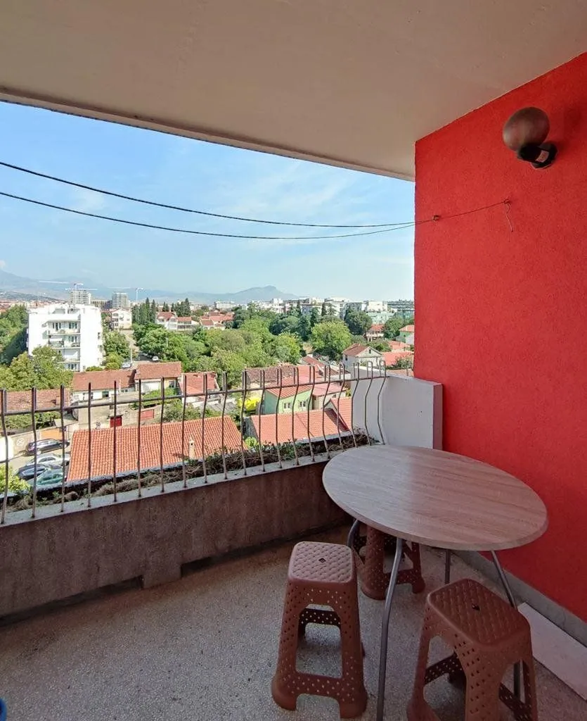 Covered balcony with a table, chairs, and a city view.