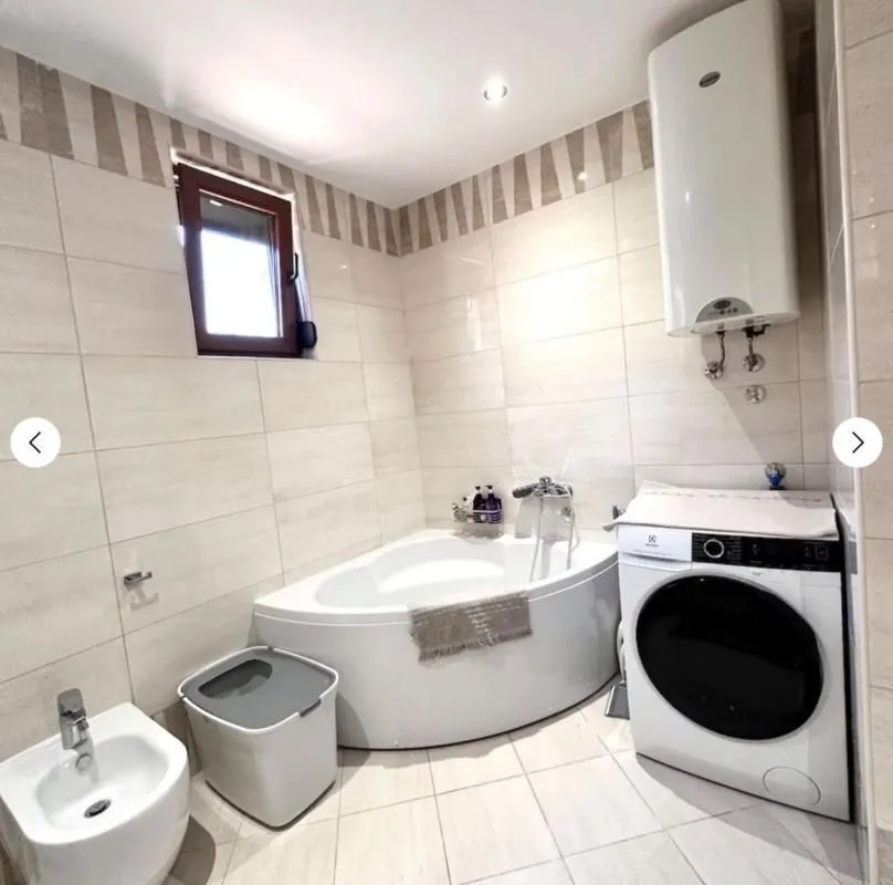 Bathroom equipped with a corner bathtub, bidet, and washing machine.