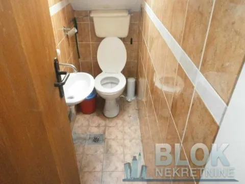 Smaller tiled bathroom with a toilet and a sink. - image 5