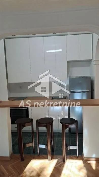 Small kitchen with white cabinets and a breakfast bar with bar stools.