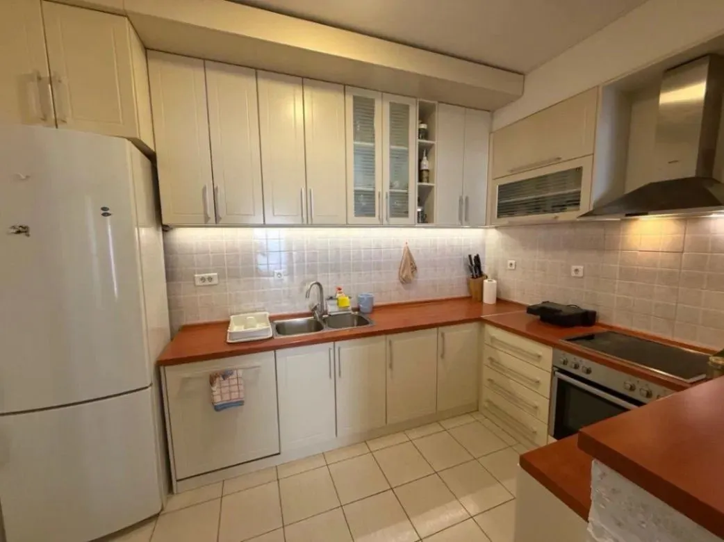 Kitchen with light cabinets, white appliances, and a red countertop.