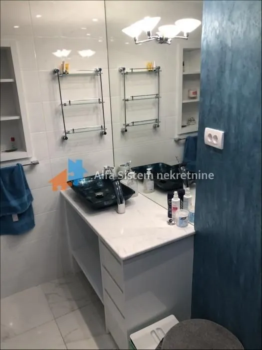 Bathroom with a sink, mirror, and storage shelves.