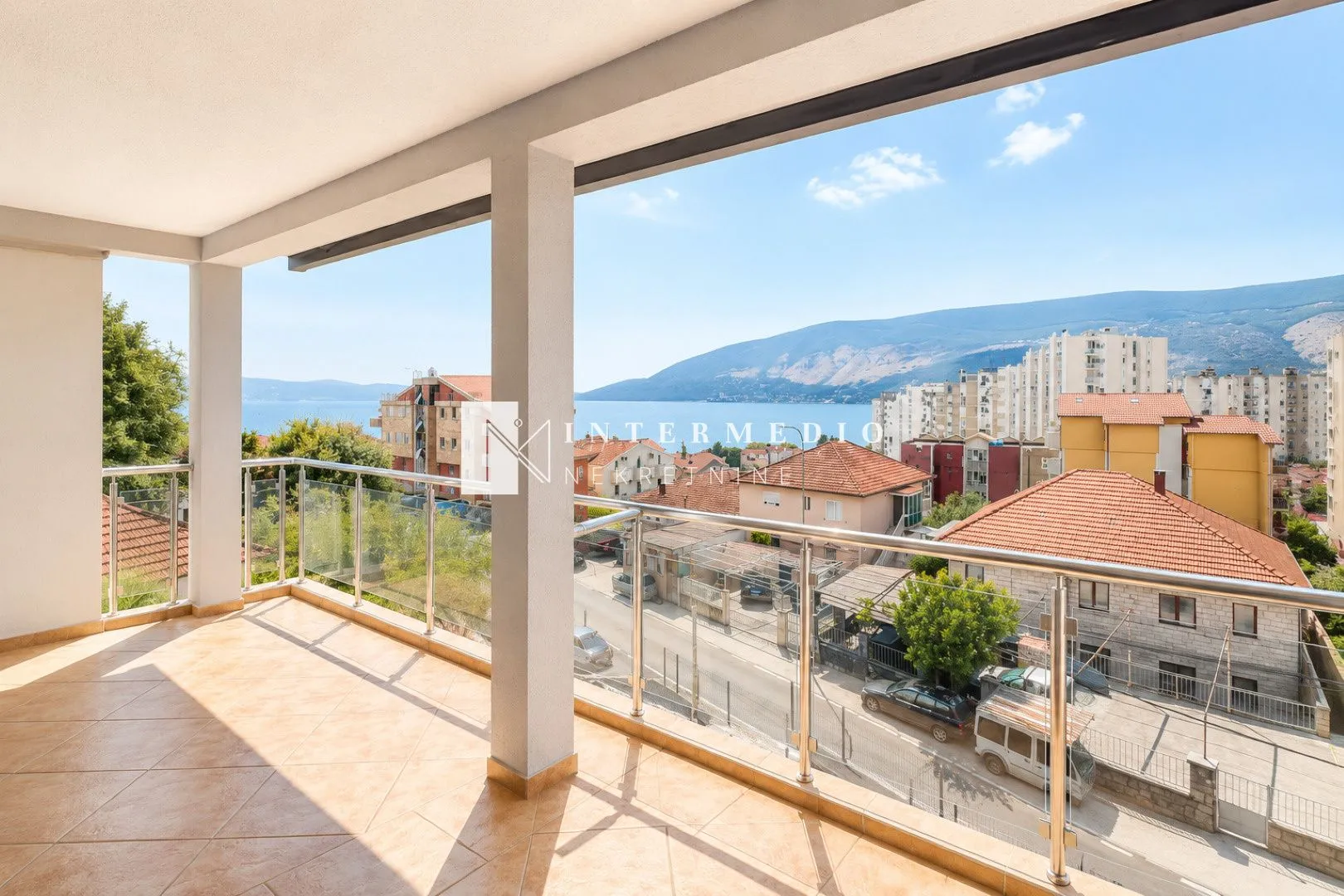 Prostrani natkriveni balkon sa pogledom na more i grad.