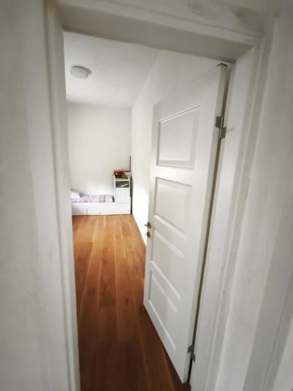 View from the hallway into a bedroom with wooden flooring.
