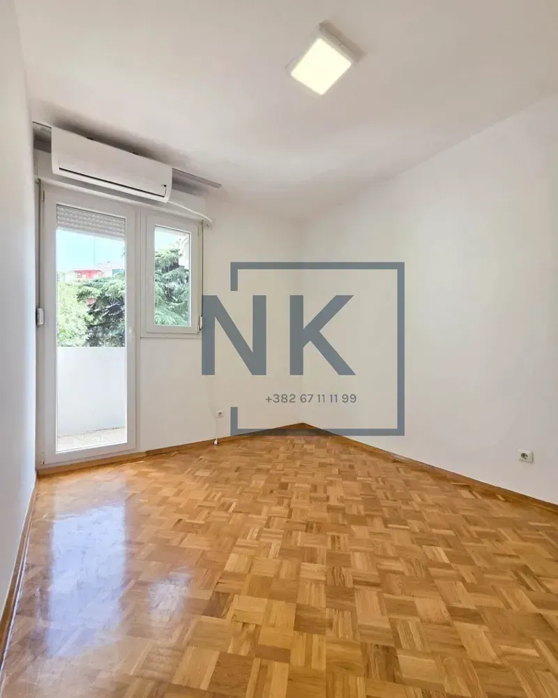 Empty room with parquet flooring and balcony access.