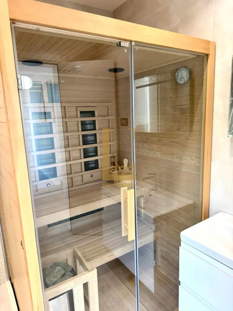 Moderna kućna sauna sa drvenim oblogama i staklenim vratima.