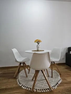 A small round dining table with three white chairs on a decorative rug. - image 2