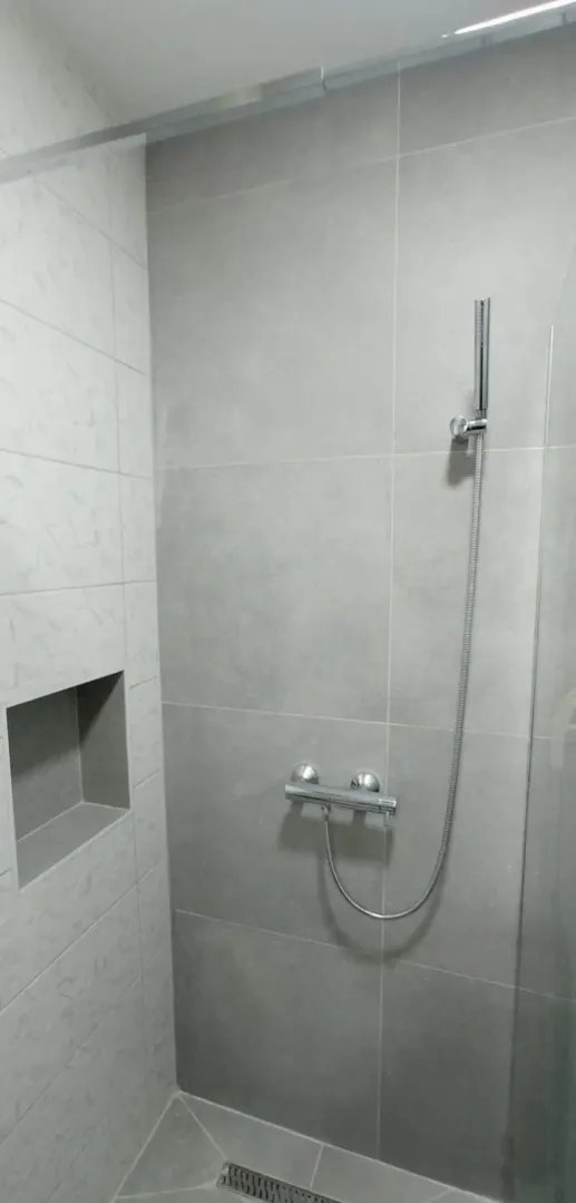Moderno opremljena tuš kabina sa sivim pločicama.