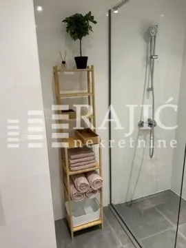 Modernly furnished bathroom with a shower cabin and a wooden shelf. - image 2