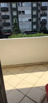 Pogled sa popločanog balkona prema zgradi i zelenilu. - image 6