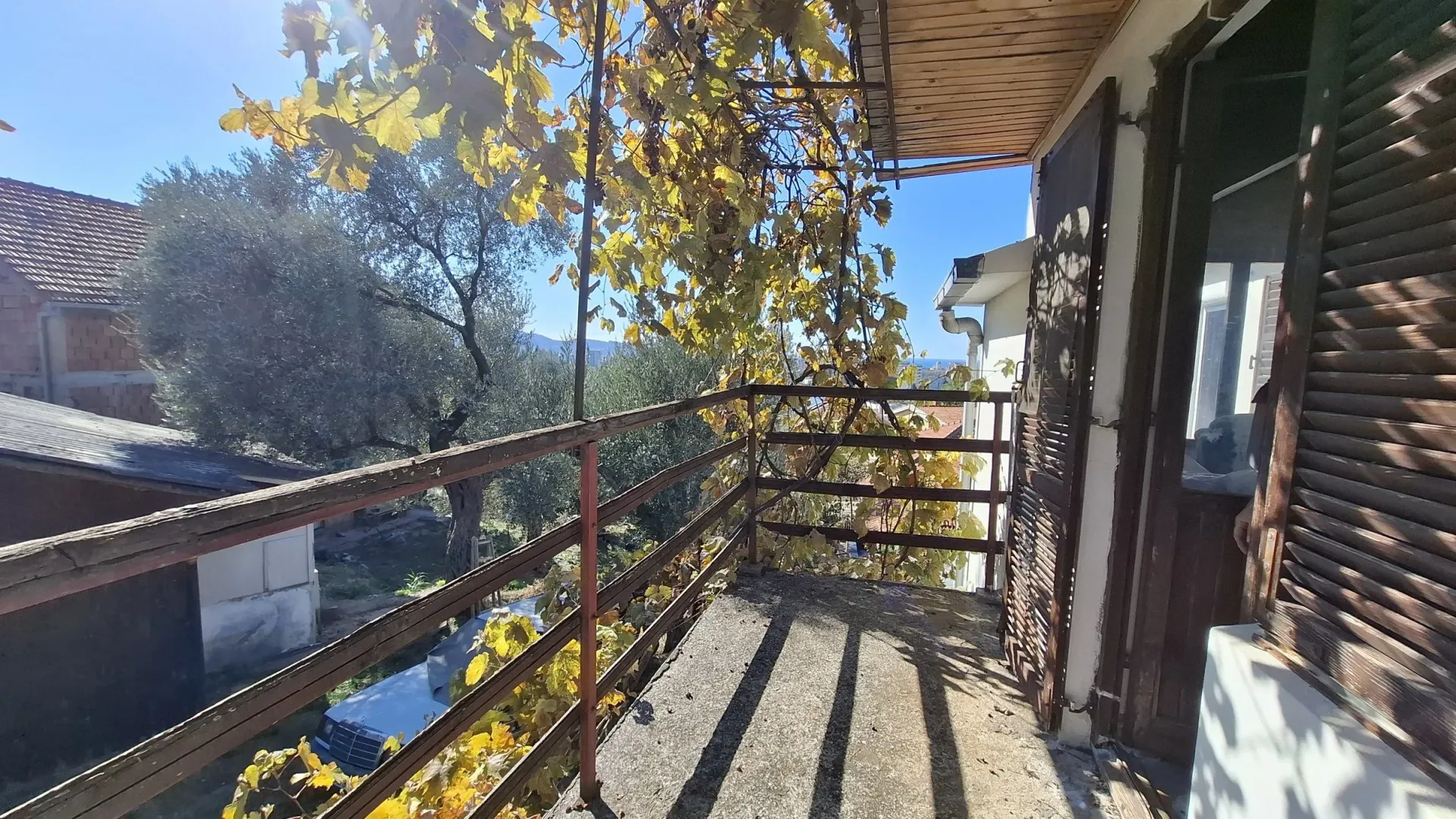 Terasa sa drvenom ogradom i pogledom na prirodu i dvorište.