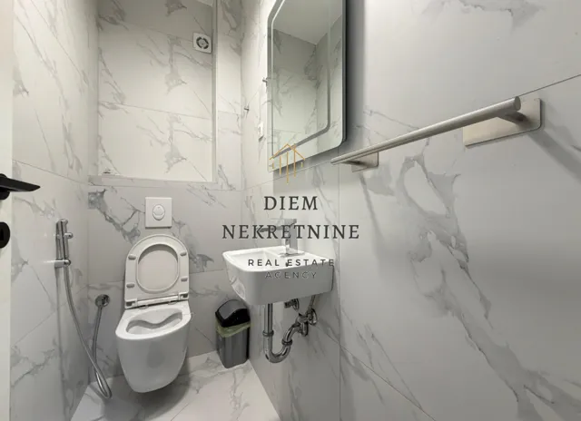Small bathroom with a toilet, washbasin, and marble tiles.