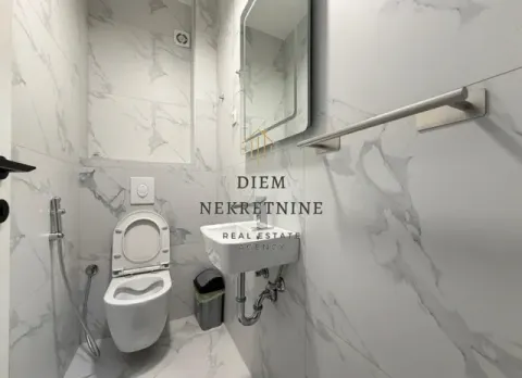 Small bathroom with a toilet, washbasin, and marble tiles. - image 12